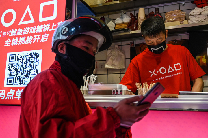 Pengantar makanan menunggu di toko kecil untuk dalgona, permen gula renyah yang ditampilkan dalam serial Netflix, Squid Game, di Shanghai, pada 12 Oktober 2021.