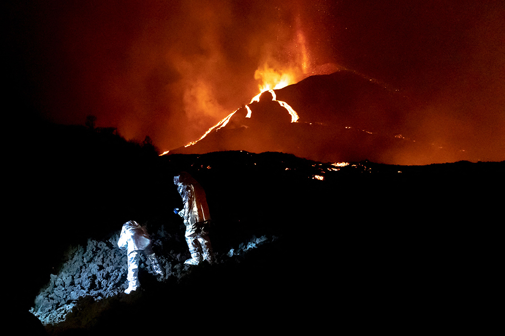 Dalam foto selebaran yang diambil dan dirilis oleh Unit Darurat Militer Spanyol (UME) pada 16 Oktober 2021, anggota GIETMA (Kelompok Intervensi Darurat Teknologi dan Lingkungan) UME memantau evolusi aliran lava baru, setelah letusan gunung berapi Cumbre Vieja, di pulau Canary La Palma. 