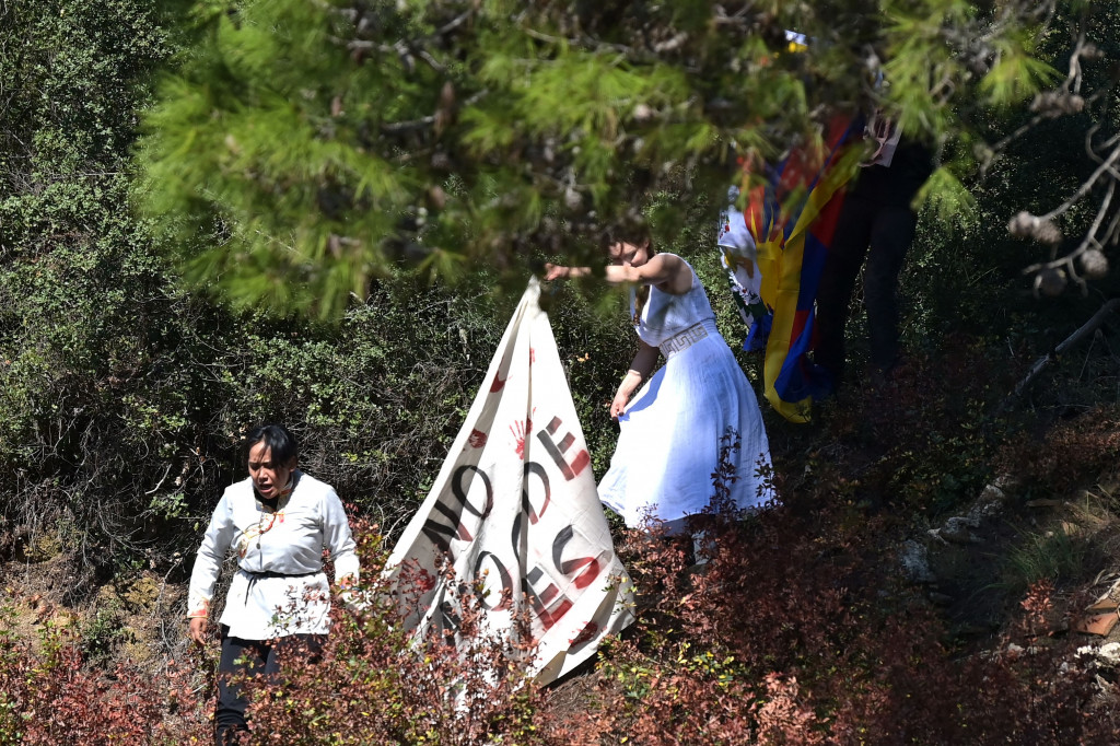 Tiga pengunjuk rasa berteriak untuk memboikot Olimpiade di Beijing, ketika pejabat yang diundang, termasuk Presiden Yunani Katerina Sakellaropoulou dan Presiden Komite Olimpiade Internasional Thomas Bach, melihatnya.