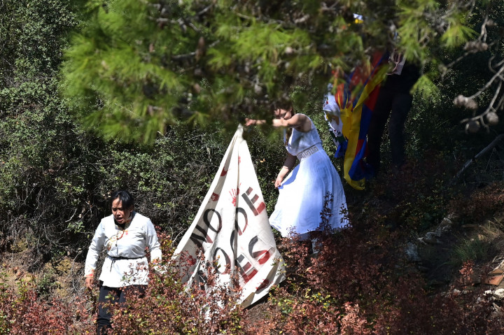 Tiga pengunjuk rasa berteriak untuk memboikot Olimpiade di Beijing, ketika pejabat yang diundang, termasuk Presiden Yunani Katerina Sakellaropoulou dan Presiden Komite Olimpiade Internasional Thomas Bach, melihatnya.