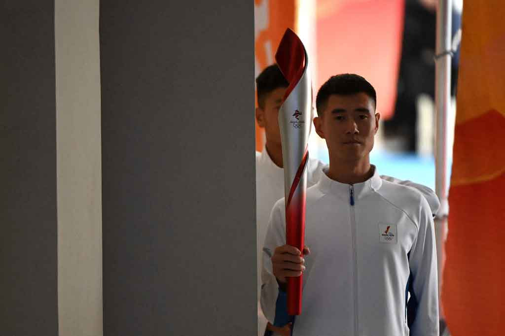 Pembawa obor memasuki panggung saat upacara penyambutan nyala api Olimpiade menjelang Olimpiade Musim Dingin Beijing 2022, di lobi Menara Olimpiade di Beijing pada 20 Oktober 2021.