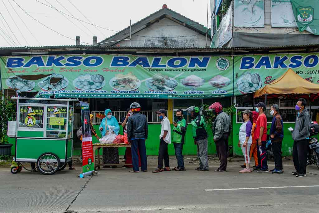 Sejumlah warga mengantre untuk mendapatkan bubur ayam gratis di kawasan Kukusan, Depok, Jawa Barat, Rabu, 27 Oktober 2021.