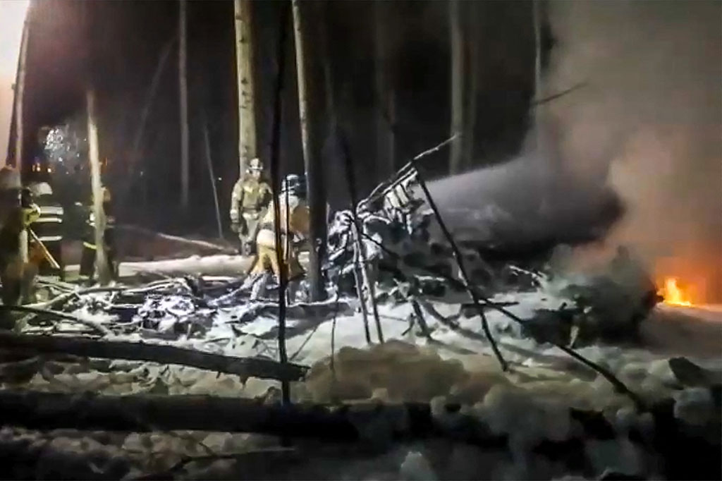 Petugas bekerja keras memadamkan api di lokasi kecelakaan pesawat Antonov An-12 di luar Kota Irkutsk, Siberia, Rabu, 3 Oktober 2021 waktu setempat. Petugas bekerja diterangi obor di tengah kondisi yang gelap dan bersalju.