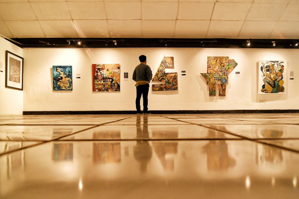 Pengunjung mengamati lukisan yang ditampilkan dalam pameran bertajuk 