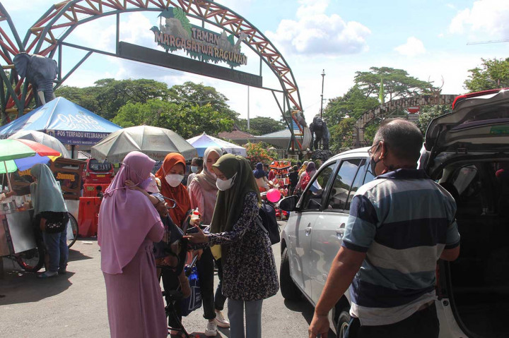Warga masyarakat yang mengisi waktu liburannya saat akan masuk objek wisata Taman Margasatwa Ragunan di Pintu Masuk Taman Margasatwa Ragunan, Jakarta, Minggu, 14 November 2021. 