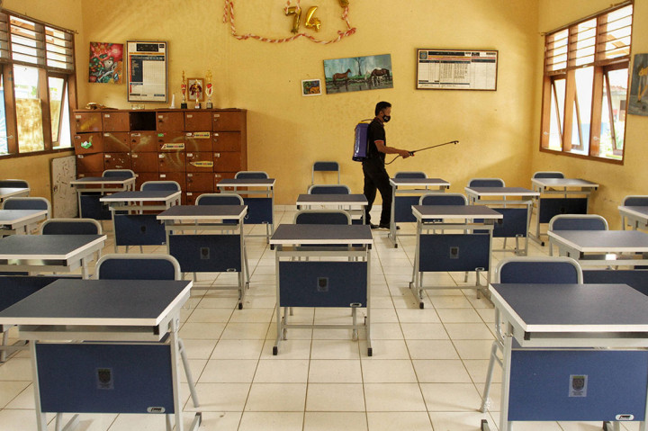 Pekerja menyemprotkan disinfektan di ruang kelas di SMPN 2 Depok, Pancoran Mas, Depok, Jawa Barat, Jumat, 19 November 2021.