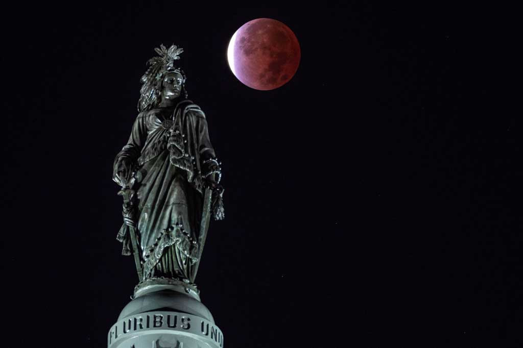 Penampakan gerhana Bulan sebagian terlihat dari Patung Kebebasan, di atas gedung Capitol Hill, Washington, DC, Amerika Serikat. AFP PHOTO/Andrew Cabello-Reynolds