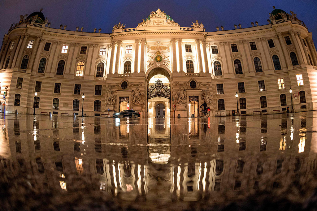 Seorang pengendara sepeda melewati Istana Hofburg di alun-alun Michaeler di Wina, Austria yang tampak sepi pada Senin, 22 November 2021 waktu setempat. 