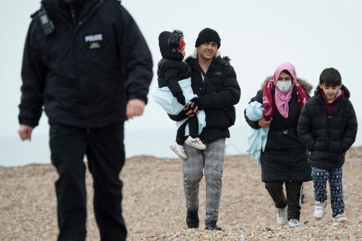 Para migran berjalan di sepanjang pantai setelah dibantu ke darat dari sekoci RNLI (Royal National Lifeboat Institution) menyusul penyelamatan mereka saat melintasi Selat Inggris di Dungeness, Inggris tenggara, Rabu, 24 November 2021.