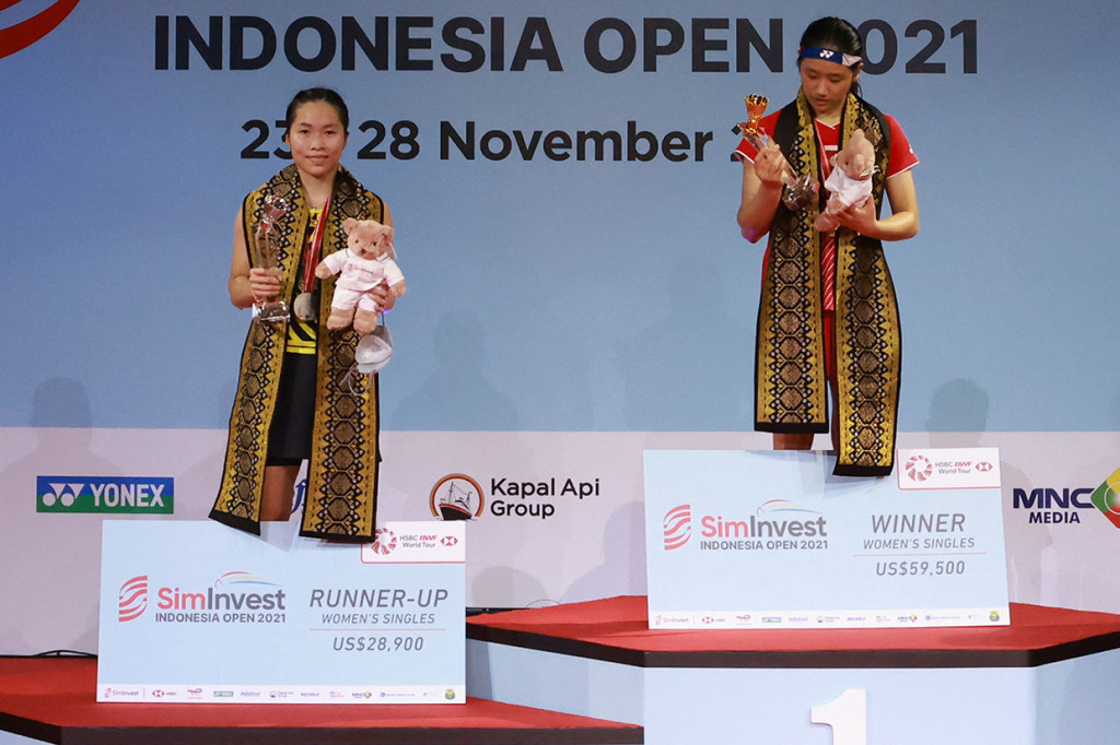 Juara tunggal putri asal Korea Selatan An Se-young (kanan) dan runner-up asal Thailand Ratchanok Intanon (kiri) berada di atas podium usai pertandingan di Indonesia Open di Nusa Dua, di pulau resor Bali, Minggu, 28 November 2021.