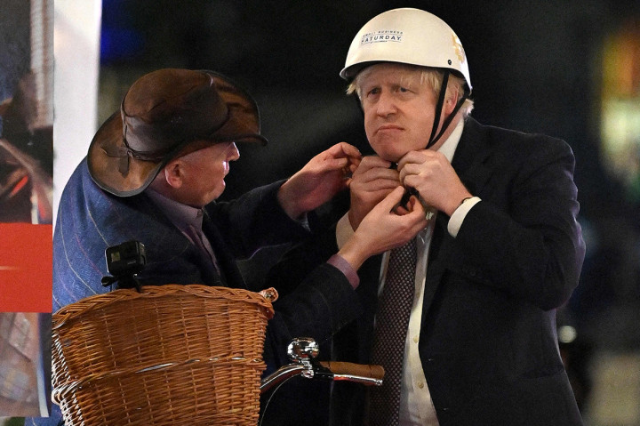 Perdana Menteri Inggris Boris Johnson memakai helm sebelum mengendarai sepeda saat kunjungannya ke pasar Makanan dan Minuman Inggris di Downing Street, London, 30 November 2021.