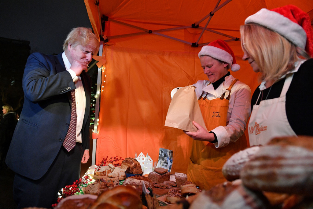 Perdana Menteri Inggris Boris Johnson (kiri) berbincang dengan pemilik kios selama kunjungannya ke pasar Makanan dan Minuman Inggris yang didirikan di Downing Street, London pusat pada 30 November 2021. 