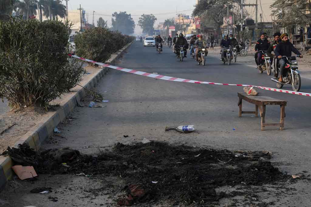 Warga melintasi area yang ditutup garis polisi di lokasi di mana seorang manajer pabrik asal Sri Lanka sebelumnya dipukuli hingga tewas oleh massa di luar sebuah pabrik di Sialkot, pada Sabtu, 4 Desember 2021.