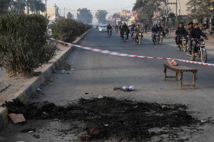 Warga melintasi area yang ditutup garis polisi di lokasi di mana seorang manajer pabrik asal Sri Lanka sebelumnya dipukuli hingga tewas oleh massa di luar sebuah pabrik di Sialkot, pada Sabtu, 4 Desember 2021.
