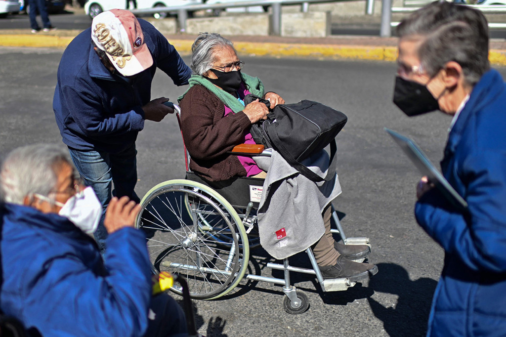 Seorang wanita di kursi roda tiba untuk disuntik dosis ketiga vaksin Covid-19 AstraZeneca di Centro de Estudios Superiores Navales (CENCIS) di Ibu Kota Meksiko, Mexico City, Selasa, 7 Desember 2021.