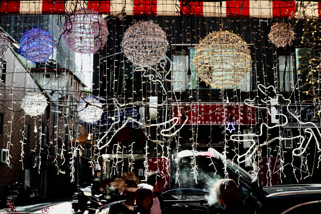 Orang-orang berdiri di luar toko yang menawarkan dekorasi Natal untuk dijual di sebuah pasar di Taipei, Rabu, 8 Desember 2021. 