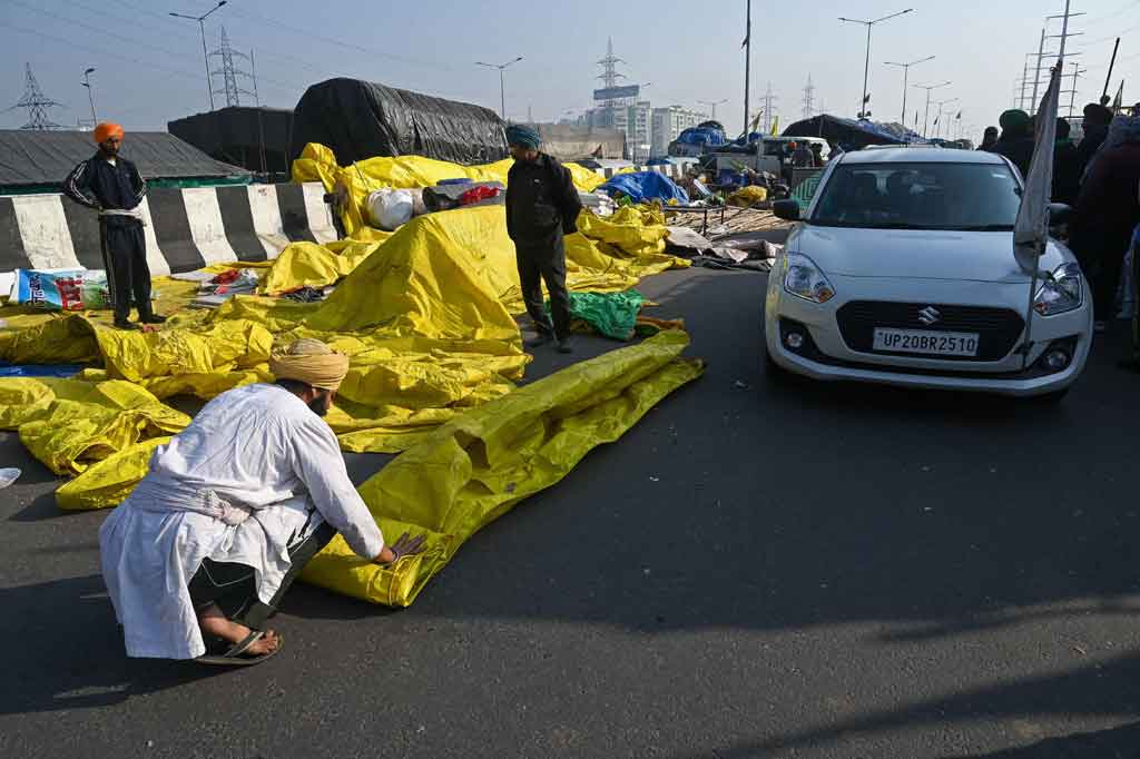 Ratusan petani menari dan merayakan kemenangan Sabtu pagi saat mereka mulai menghilangkan penghalang jalan dan membongkar ribuan rumah darurat di sepanjang jalan raya utama.