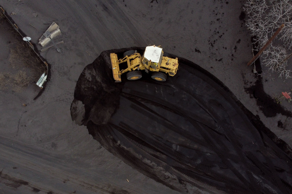 Sebuah ekskavator mengeluarkan abu dari jalan yang tertutup lahar dan abu setelah letusan gunung berapi Cumbre Vieja, di Las Manchas, di Pulau Canary La Palma pada 14 Desember 2021.