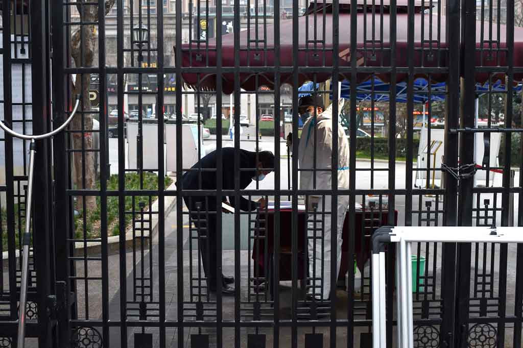 Seorang penjaga keamanan memeriksa informasi seorang penduduk di pintu masuk area pemukiman yang berada di bawah pembatasan menyusul penemuan wabah covid-19  baru-baru ini di Xian, Provinsi Shaanxi, Tiongkok, Kamis, 23 Desember 2021.