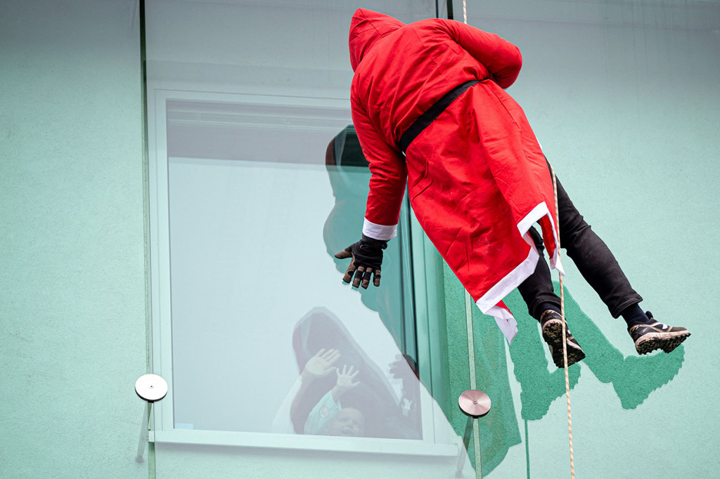 Seseorang yang menyamar sebagai Sinterklas menyapa anak-anak saat menuruni gedung klinik anak di Ljubljana, Slovenia, Rabu, 22 Desember 2021.