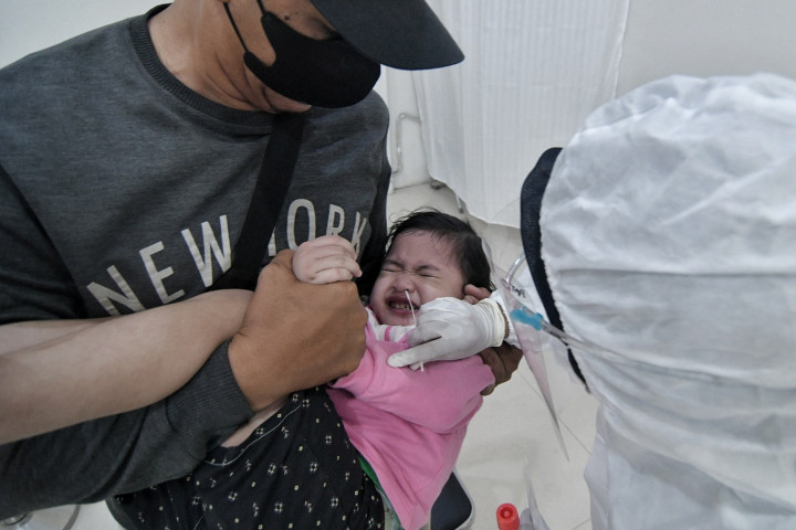Petugas kesehatan melakukan tes swab PCR pada seorang anak di Stasiun Pasar Senen, Jakarta, Kamis, 23 Desember 2021.