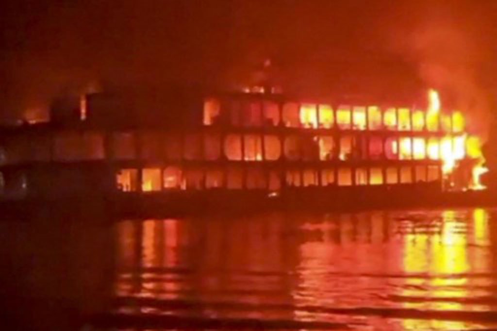 Warga menyaksikan bangkai feri yang hangus terbakar di Jhakakathi, 250 kilometer (160 mil) selatan Dhaka, Bangladesh, Jumat, 24 Desember 2021. Kecelakaan tersebut mengakibatkan sedikitnya 32 orang meninggal dunia.