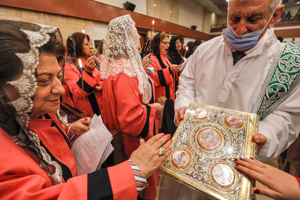 Seorang jemaat mengulurkan tangan untuk menerima berkat selama misa malam Natal di Gereja Ortodoks Suriah Um al-Noor di Arbil, ibu kota wilayah otonomi Kurdi, Irak utara, pada Jumat, 24 Desember 2021.