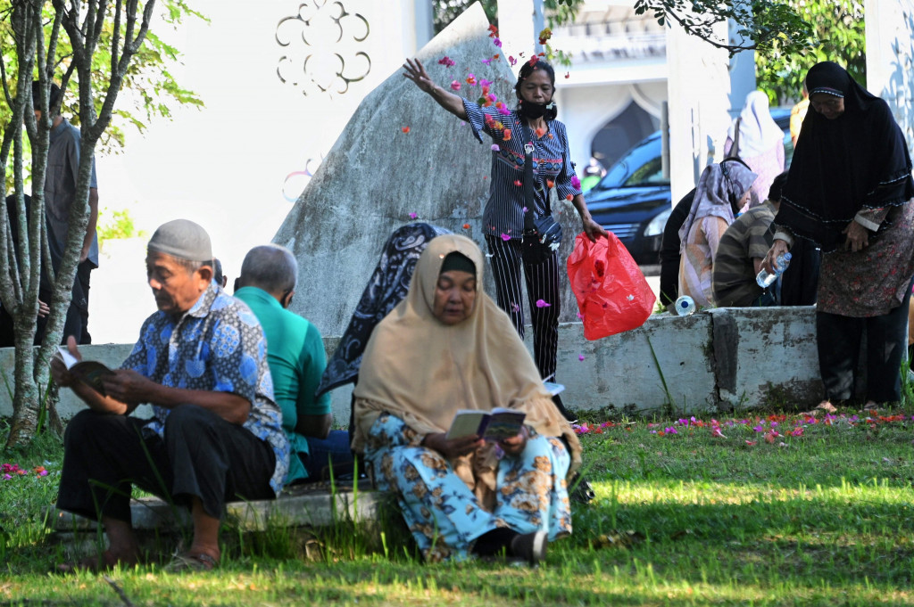 Orang-orang mengunjungi pemakaman massal di Taman Peringatan Tsunami Siron di Siron, provinsi Aceh pada 26 Desember 2021, untuk menandai peringatan gempa dan tsunami 17 tahun lalu yang mengakibatkan ratusan ribu korban jiwa di 13 negara yang terdampak. 