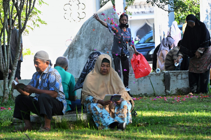 Orang-orang mengunjungi pemakaman massal di Taman Peringatan Tsunami Siron di Siron, provinsi Aceh pada 26 Desember 2021, untuk menandai peringatan gempa dan tsunami 17 tahun lalu yang mengakibatkan ratusan ribu korban jiwa di 13 negara yang terdampak. 