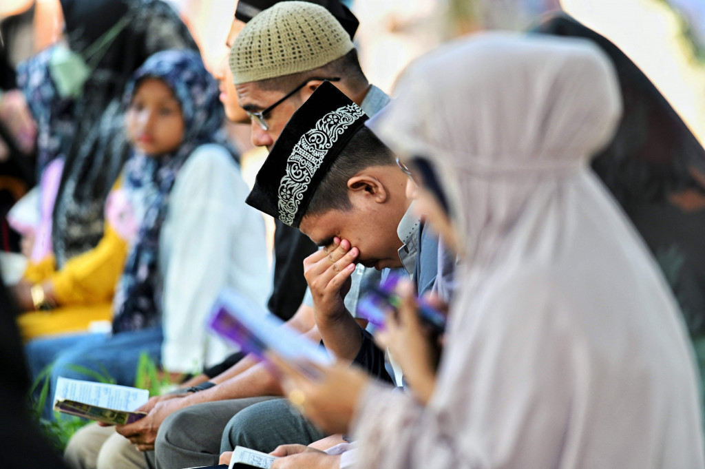 Sejumlah warga berdoa untuk keluarganya yang meninggal akibat bencana gempa dan tsunami di kuburan massal korban tsunami Aceh Besar, Aceh, Minggu, 26 Desember 2021.