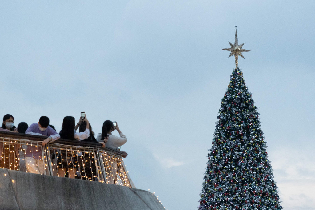 Orang-orang mengambil foto pohon natal raksasa selama natal di distrik budaya West Kowloon di Hong Kong, 25 Desember 2021.