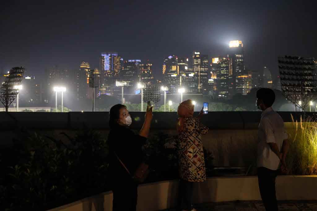 Pengunjung antri mengabadikan gambar dengar latar pemandangan kota Jakarta saat mendatangi Skywalk Senayan Park, Jakarta, Selasa, 28 Desember 2021.