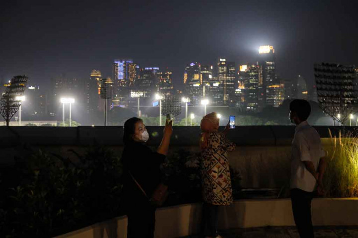 Pengunjung antri mengabadikan gambar dengar latar pemandangan kota Jakarta saat mendatangi Skywalk Senayan Park, Jakarta, Selasa, 28 Desember 2021.