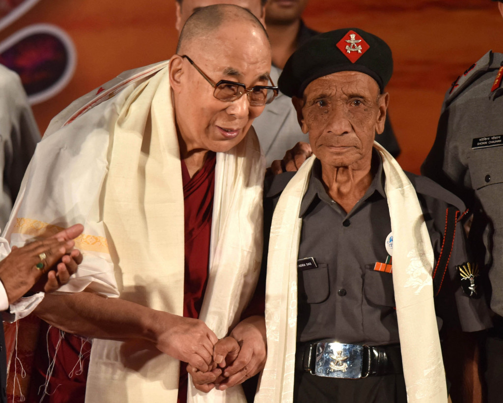 Pemimpin spiritual Tibet Dalai Lama (kiri) berjabat tangan dengan pensiunan personel Assam Rifles, Naren Chandra Das, satu-satunya yang diketahui selamat dari kelompok tujuh personel India yang pertama menerima Dalai Lama di tanah India setelah ia melarikan diri dari Tibet.
