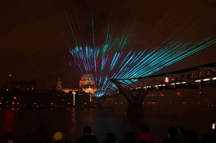 Pertunjukan laser di atas Jembatan Milenium dengan latar belakang Katedral St Paul di pusat kota London pada 1 Januari 2022 dini hari waktu setempat. AFP PHOTO/Hollie Adams
