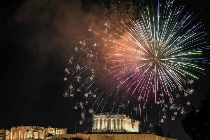 Kembang api menerangi langit di atas Acropolis Kuno di Athena, Yunani saat perayaan Malam Tahun Baru pada 31 Desember 2021. AFP PHOTO/Louisa Gouliamaki