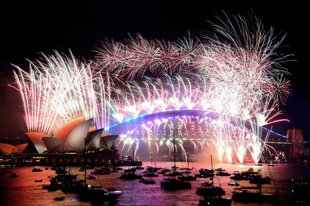 Kembang api Malam Tahun Baru menerangi langit di atas Harbour Bridge dan Opera House, Sydney pada 1 Januari 2022 dini hari waktu setempat. AFP PHOTO/David Gray