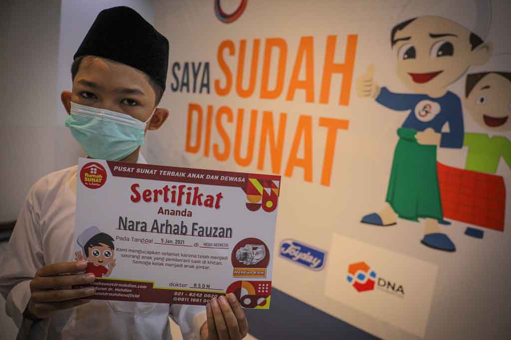 Peserta meninjukkan sertiikat seusai mengikuti khitanan massal di kantor Media Indonesia Jakarta.