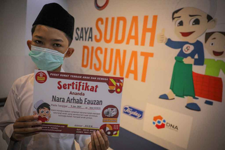 Peserta meninjukkan sertiikat seusai mengikuti khitanan massal di kantor Media Indonesia Jakarta.