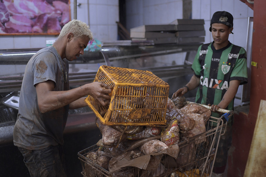 Warga memindahkan barang-barang yang rusak dan makanan busuk setelah banjir di Raposos, negara bagian Minas Gerais, Brasil, Selasa, 11 Januari 2022.