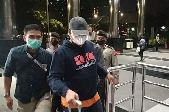 Iskandar yang mengenakan baju dan celana berwarna biru dan topi berwarna abu-abu, serta sebuah tas berwarna oranye bergegas masuk ke dalam gedung KPK.