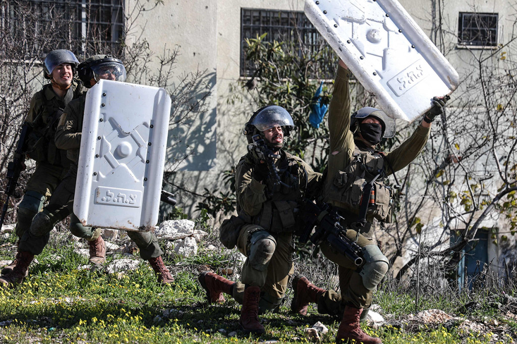 Anggota pasukan keamanan Israel menggunakan perisai untuk melindungi diri mereka dari batu saat bentrok dengan pengunjuk rasa Palestina pada demonstrasi menentang pengambilalihan tanah oleh Israel dekat permukiman Yahudi Kadumim di Desa Kfar Qaddum, Tepi Barat, 21 Januari 2022.