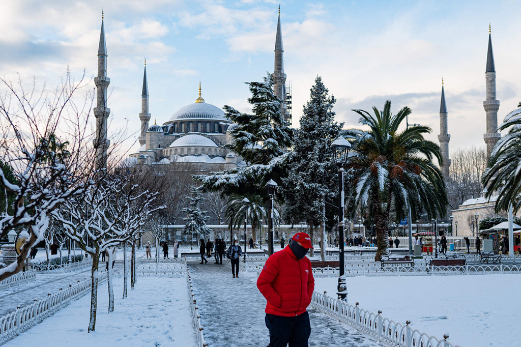 Orang-orang berjalan di alun-alun yang tertutup salju di depan Masjid Biru di Istanbul pada 23 Januari 2022.