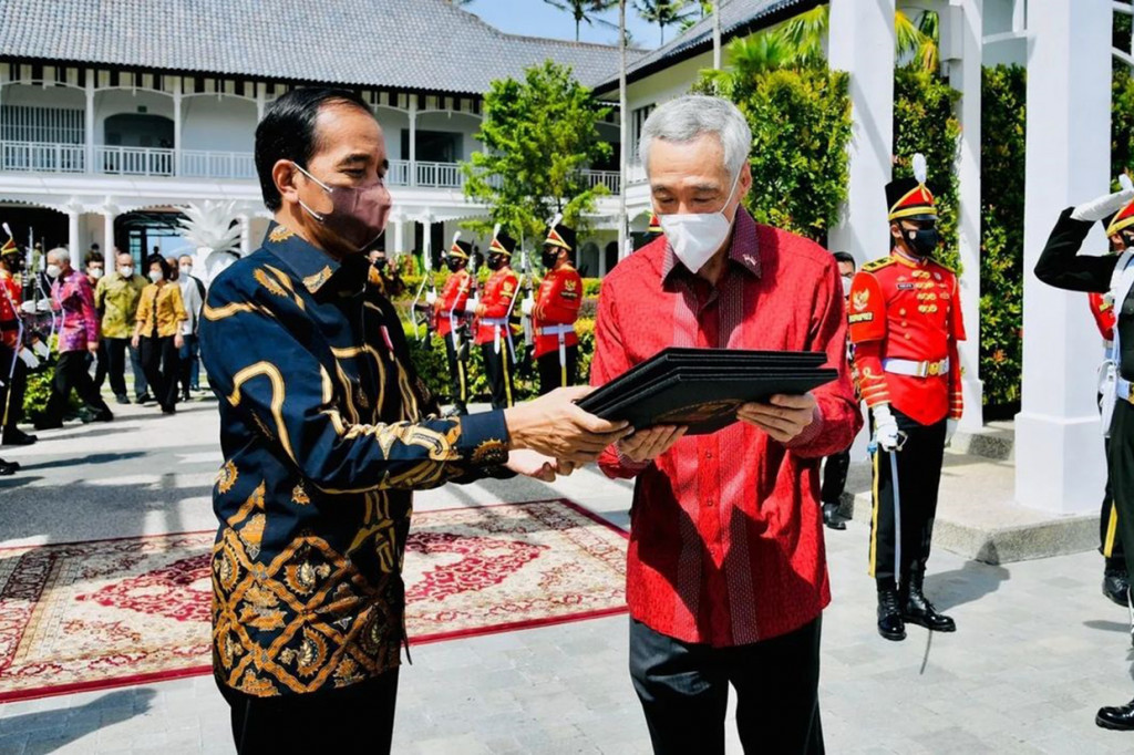 Tampak Presiden Jokowi memberikan album foto yang memuat foto-foto selama acara pertemuan kepada PM Lee.