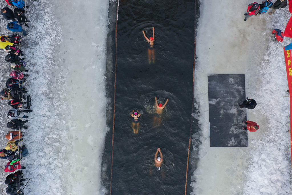 Foto udara pada 25 Januari 2022 menunjukkan penggemar renang musim dingin berenang di danau yang sebagian beku di Shenyang, Provinsi Liaoning, Tiongkok.