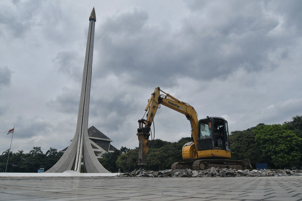 Pekerja menggunakan alat berat sedang menyelesaikan pengerjaan renovasi di Taman Mini Indonesia Indah, Jakarta, Rabu, 26 Januari 2022. 