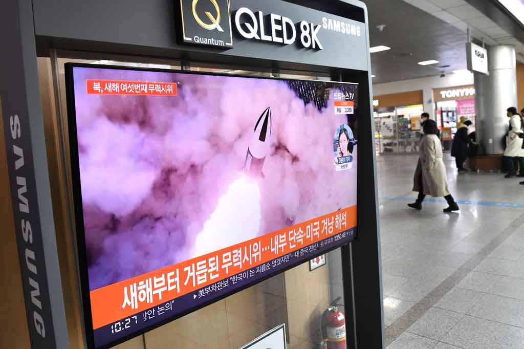 Orang-orang berjalan melewati layar televisi yang menunjukkan siaran berita dengan rekaman file uji coba rudal Korea Utara, di stasiun kereta api di Seoul, Korea Selatan pada Kamis, 27 Januari 2022.