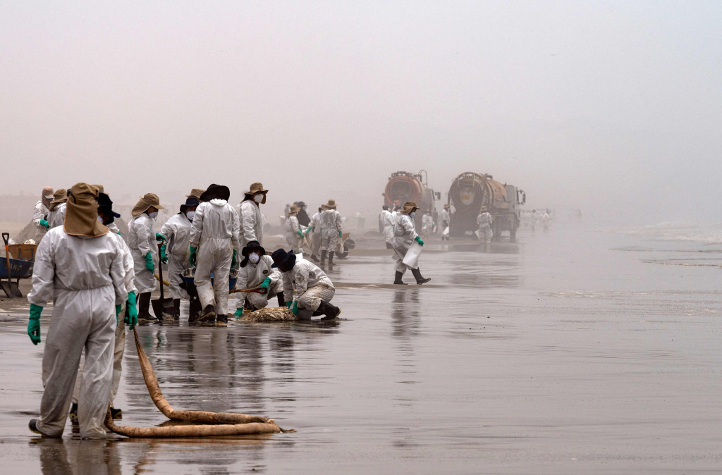 Petugas kebersihan bekerja untuk mengeluarkan minyak dari Pantai Cavero di Callao, Peru, 26 Januari 2022.