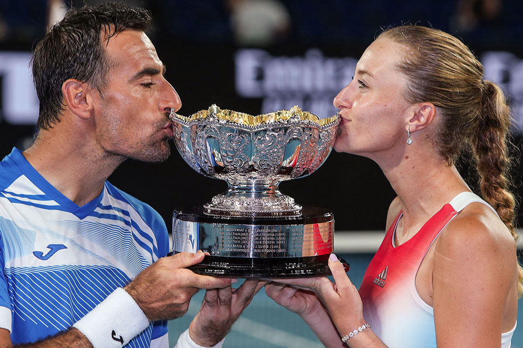 Kristina Mladenovic dari Prancis dan Ivan Dodig dari Kroasia mencium trofi yang baru saja mereka raih di turnamen tenis Australian Open, Jumat, 28 Januari 2022.