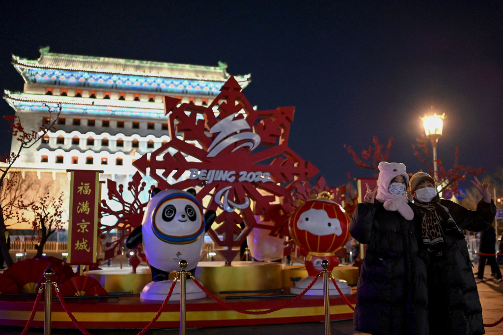 Orang-orang berpose di depan instalasi yang menampilkan Bing Dwen Dwen (kiri) dan Shuey Rhon Rhon (kanan), masing-masing maskot Olimpiade Musim Dingin dan Paralimpiade Beijing 2022, di Beijing pada 31 Januari 2022.